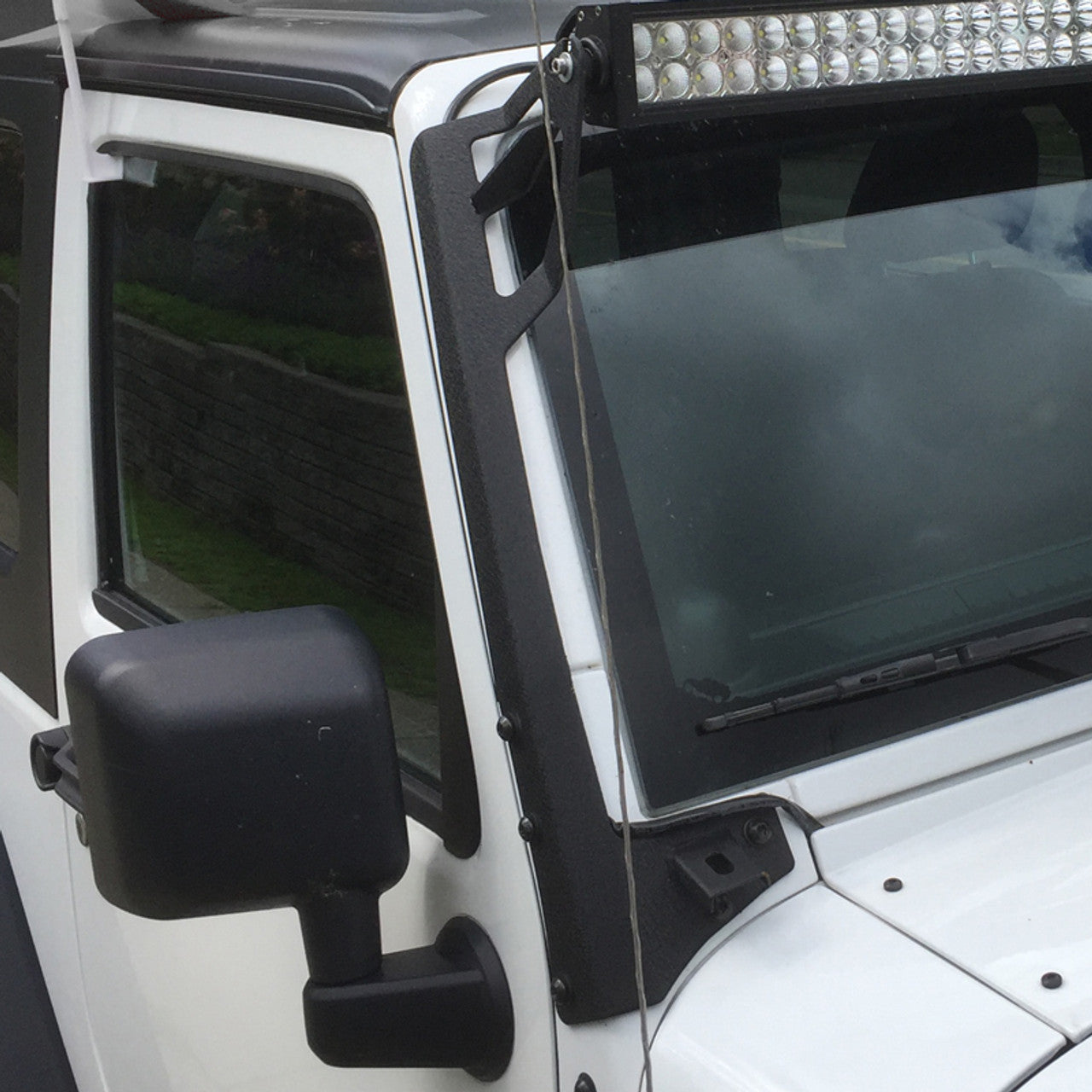 close-up of 2007–2018 Jeep Wrangler JK A-pillar light mount brackets installed on white Jeep Wrangler